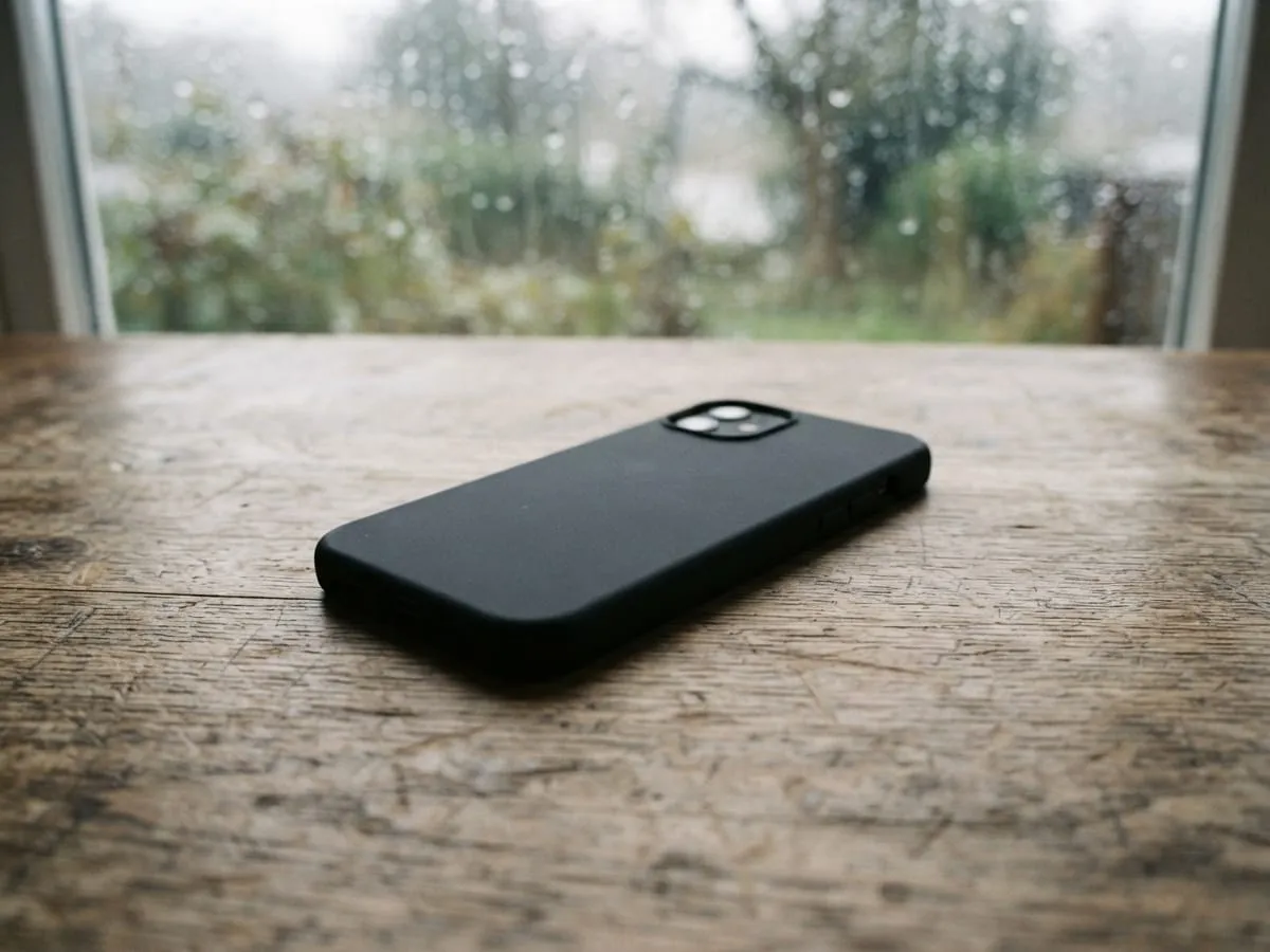 A phone lying face down on a wooden table